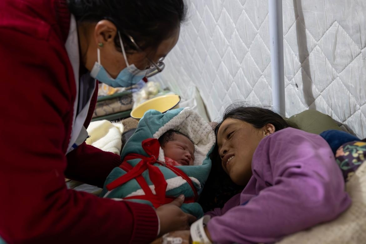 1月10日，定日縣中心醫(yī)院的婦產科醫(yī)生悉心照看一位母親和她懷里的新生兒。人民日報記者張武軍攝