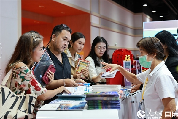 外國觀眾在中國展臺(tái)仔細(xì)閱讀赴華旅游介紹，向工作人員咨詢關(guān)于中國美食和景點(diǎn)的詳細(xì)信息。人民網(wǎng)記者 白元琪攝