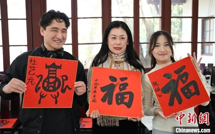 1月20日，外籍留學(xué)生和西泠印社社員李硯(中)展示各自創(chuàng)作的福貼。當(dāng)日，來自巴西、馬來西亞、加納、哈薩克斯坦的外籍留學(xué)生在浙江杭州西泠印社體驗福貼、春聯(lián)和篆刻，感受古老的中國傳統(tǒng)文化。中新社記者 王剛 攝