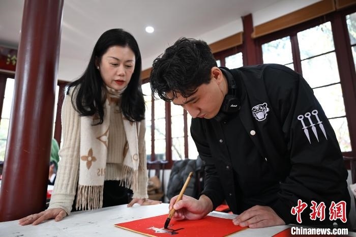 1月20日，外籍留學(xué)生在西泠印社社員李硯指導(dǎo)下寫福。當(dāng)日，來自巴西、馬來西亞、加納、哈薩克斯坦的外籍留學(xué)生在浙江杭州西泠印社體驗福貼、春聯(lián)和篆刻，感受古老的中國傳統(tǒng)文化。中新社記者 王剛 攝