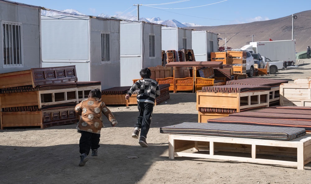 2025年1月13日，在定日縣嘎旦村，兩個(gè)孩子在剛運(yùn)來的兩排藏床間奔跑。新華社記者丁增尼達(dá) 攝