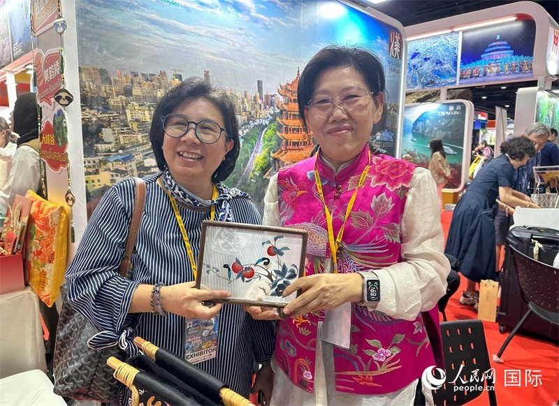 中國“大冶刺繡”傳承人劉小紅（右）參加泰國國際旅游展，向觀眾介紹中國非遺刺繡針法。人民網(wǎng)記者 簡承淵攝