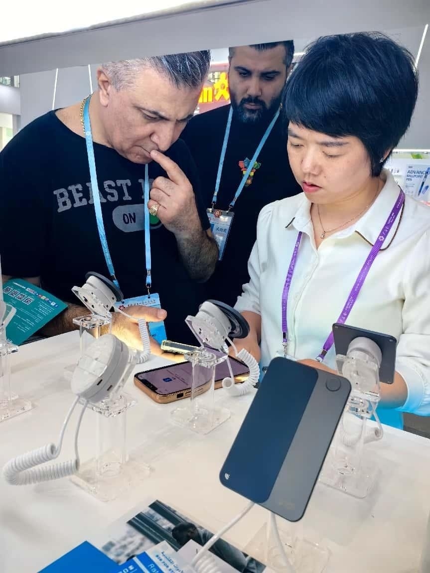 展臺(tái)工作人員向外商展示“AI TOP翻譯終端”。圖片來(lái)源：受訪者提供