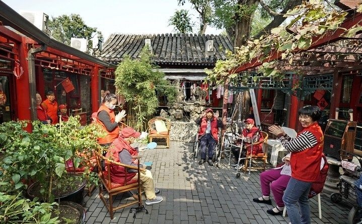 2024年10月12日，鐘樓灣胡同的老年人在社區(qū)內(nèi)的四合院養(yǎng)老驛站休閑。2017年起，北京市先后開展了兩輪背街小巷環(huán)境整治提升行動，完整保留了中軸線生活建筑群的歷史信息，并根據(jù)居民的生活和居住方式進(jìn)行適配化的更新和改造，極大地改善了生活環(huán)境。2023年鐘樓灣胡同被評為“北京最美街巷”。