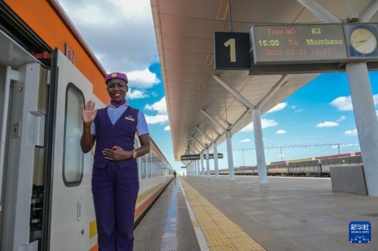 5月31日，在蒙內(nèi)鐵路內(nèi)羅畢站，一名乘務(wù)員在即將開往蒙巴薩的E2次列車旁等候乘客。新華社記者 楊光 攝
