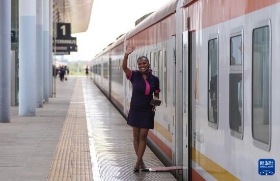 5月31日，在蒙內(nèi)鐵路內(nèi)羅畢站，一名乘務(wù)員在即將開往蒙巴薩的E2次列車旁等候乘客。新華社記者 李亞輝 攝